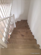 Treppe aufgesattelt mit Lichtwange aus Metall und Wandbolzen.
Geländer aus Holz